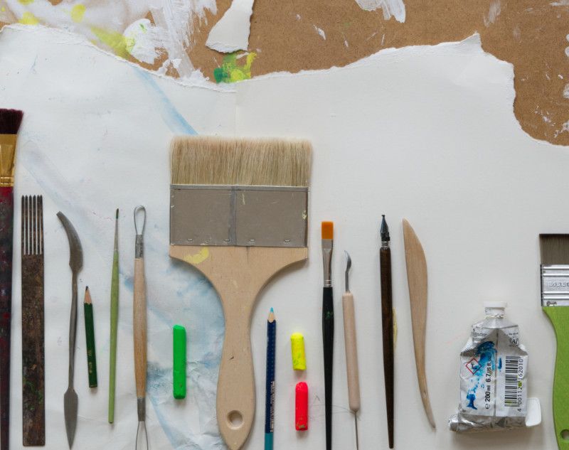 Künstlerbedarf: Pinsel, Farben, Stifte und Werkzeuge auf einer Leinwand. Kreatives Malen und Zeichnen.