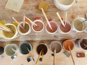 Keramik Workshop: Farbeimer und Pinsel auf Tisch. Ausstellungen & Workshops.