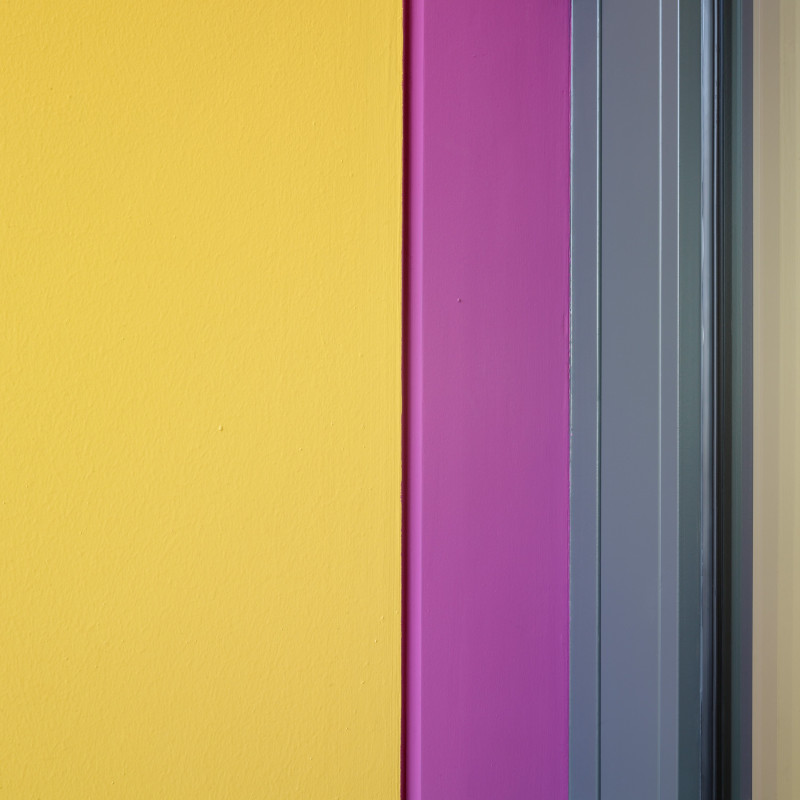 Abstrakte Farbkomposition: Gelbe Wand, pinkfarbener Rahmen, graue Zierleisten, modernes Design.