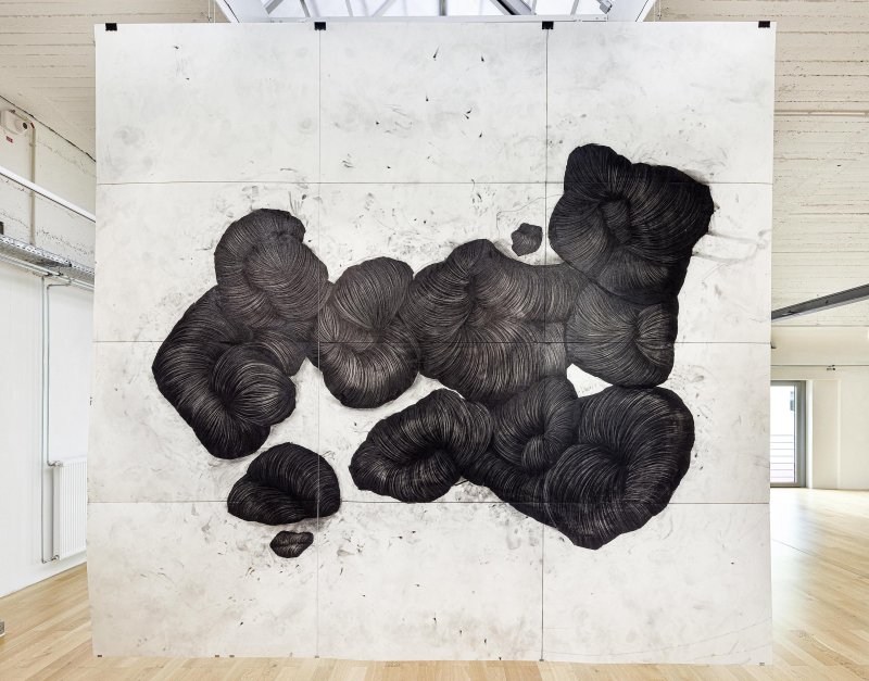 Großflächiges, abstraktes Kunstwerk mit schwarzen, organischen Linienmustern auf weißem Hintergrund in einer Galerie.